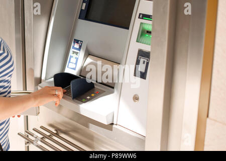 Eine Frau mit einer Kreditkarte am Geldautomaten auf der Straße. Betrieb mit Geld. Zahlung. Platz kopieren Stockfoto