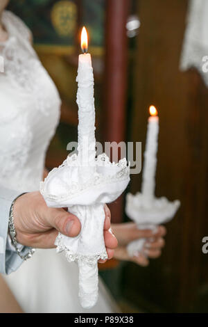Der Bräutigam und die Braut halten Kerzen in den Händen Stockfoto
