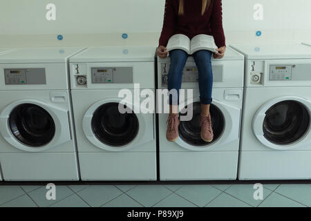 Frau mit Buch beim Waschsalon warten Stockfoto