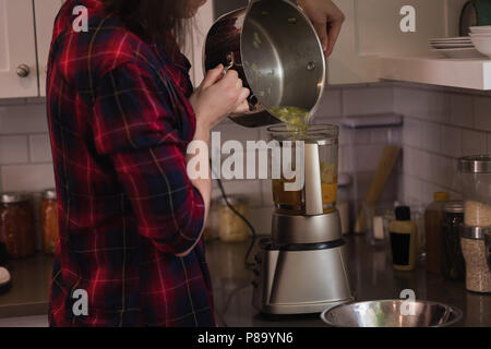 Frau mit Mixer Schleifmaschine in der Küche Stockfoto