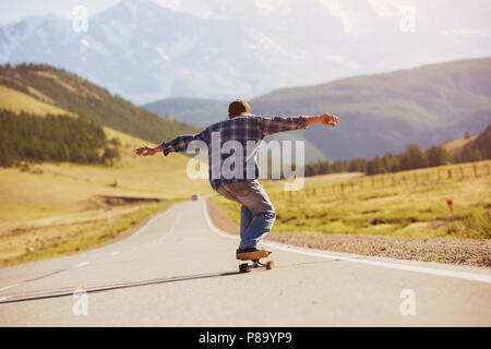 Man Schlittschuhlaufen auf Longboard gerade Mountain Road Stockfoto