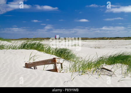 Eine Holzkiste, gewaschen an Land, im Sand dune eine neue gebildet, in der Ferne eine rote Leuchtturm Stockfoto