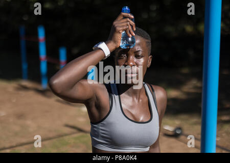 Erschöpft weiblichen Athleten mit Wasserflasche Stockfoto