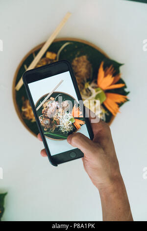 Nicht erkennbare Person, die Aufnahme der Platte mit Essen in Bangkok, Thailand. Stockfoto