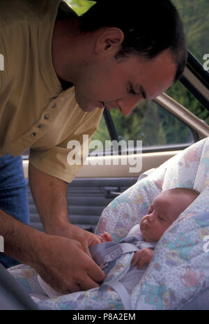 Vater baby Befestigung in Autositz Stockfoto