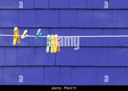 Kunststoff Zapfen auf einer Wäscheleine gegen Lila geschuppt Wand. Platz für Ihren Text. Stockfoto