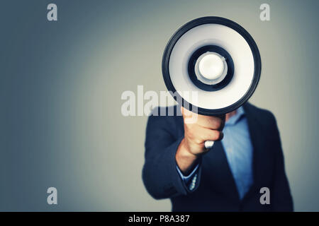 Geschäftsmann mit Megaphon in der Hand vor dem Gesicht Stockfoto