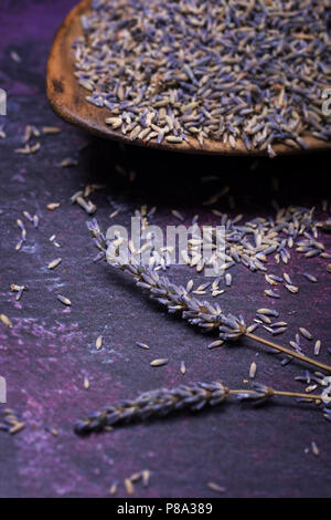 Zweige Lavendel und vereinzelte Blumen mit einer Schüssel mit getrocknetem Lavendel im Hintergrund. Selektive konzentrieren. Stockfoto