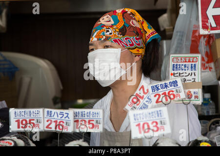 Tokyo, Japan - 26 Juni 2016: Junge Straßenverkäufer, das Tragen eines üblichen chirurgischen Maske, an einem in Tsukiji Straße Markt in Tokio. Dies ist die bigges Stockfoto