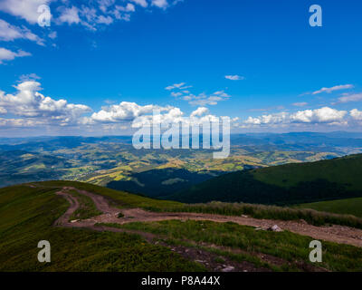 Eine herrliche Landschaft mit Bergen und Tälern mit einer unbefestigten Straße, gehen, unten von einem grünen Hang und niedrige schwimmende Wolken über all diese Schönheit. . Für yo Stockfoto