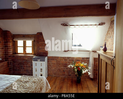 Weißen Vorhang am Fenster im Dachgeschoss Schlafzimmer mit Holzböden und unverputzte Wand unter Dachschräge Stockfoto