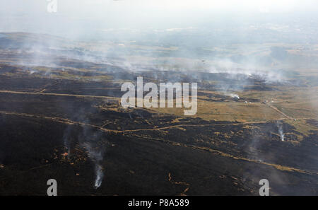 Luftaufnahme von einem Hubschrauber fallen Wasser auf moorland Brände auf Winter Hill in der Nähe von Manchester Stockfoto