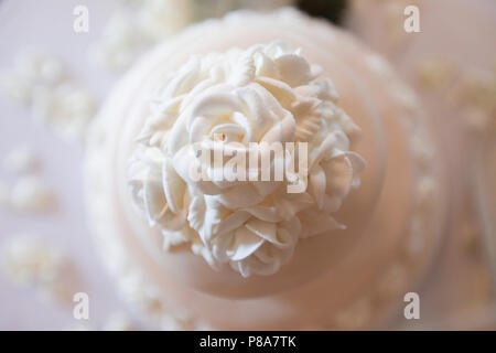 Hoher winkel Nahaufnahme der oberen Stufe einer schönen weißen Hochzeitstorte mit detaillierten weisse Rosen als Dekoration. Stockfoto