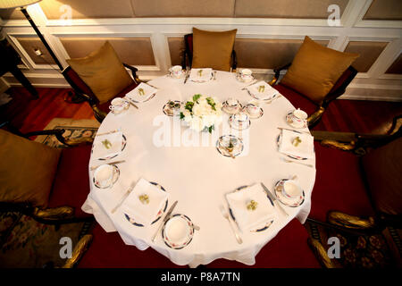 High-Angle Shot von einen großen runden Tisch, legte mit einem englischen Nachmittagstee Tabelle einstellen, Marmelade und ein Blumenstrauß auf einem weißen Tischtuch in einem... Stockfoto