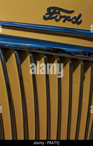 Enge close-up der klassischen alten Ford Frontgrill mit Chrom, alten Ford Logo und lebendige gelb Lackierung. Stockfoto