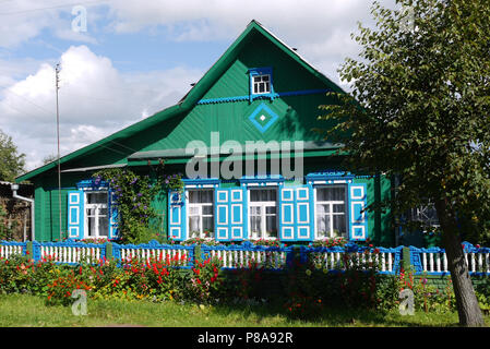 Blau oder Türkis Holzhaus mit Rollläden mit einer gemalten Zaun, Blumen und Bäume vor einem blauen bewölkten Himmel. Ort der Erholung und des Tourismus. Für Ihre d Stockfoto