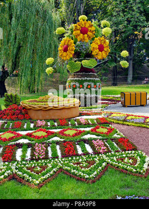 Zahlen aus leuchtend bunten Blumen auf einem flower show Schaden grüne Bäume. ein Handtuch, ein Brot, ein Blumenstrauß in einer Vase und eine Brust. Für ihr Design Stockfoto