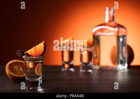 Gläser tequila mit Orange und Zimt Sticks auf einen hölzernen Tisch. Gläser, garniert mit Zucker und Zimt Pulver. Stockfoto