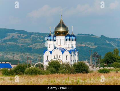 Schöne Kirche mit vier blauen und einer großen goldenen Kuppel in der Sonne vor dem Hintergrund der sanft abfallenden grünen Berge. Für ihr Design Stockfoto