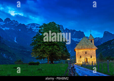 Kirche im Dorf Thethi und schneebedeckten Bergen, in der Dämmerung, am Theth Tal, Albanien Stockfoto