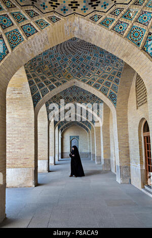 Reihe von Bögen im Innenhof der Nasir Ol Molk Moschee, auch bekannt als Rosa Moschee, mit einer iranischen Frau in lokalen Kleidern, in Shiraz, Iran Stockfoto