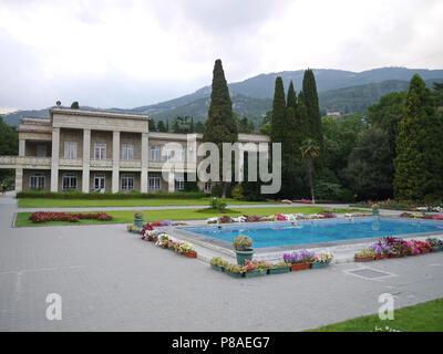 Ein sauberer Pool mit Blumentöpfen mit Blumen in einen großen Garten mit Liegewiese und ein solides Haus mit Balkon ausgestattet. Mit grünen Berghänge im d Stockfoto