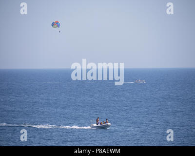 Boot mit einem Mann an einem Fallschirm und ein Motorboot in der Mitte des Meeres. Für ihr Design Stockfoto