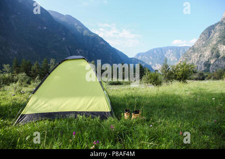 Zelt mit Schuhen auf grünem Gras in herrlicher Bergwelt, Altai, Russland Stockfoto