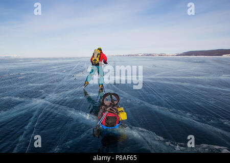 Männliche Wanderer mit Rucksack zu Fuß auf Eis Wasser Oberfläche, Russland, Baikalsee Stockfoto