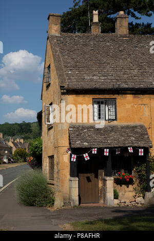 Broadway in den Cotswolds, Vereinigtes Königreich. Broadway Dorf liegt unter Fisch Hill auf der westlichen Cotswold Escarpment. Der "breite Weg" ist die breite Gras gesäumten Hauptstraße, zentriert auf dem Grün, der mit roten Kastanien und Honig gesäumt ist - farbige Cotswold Kalkstein Gebäude, viele, die aus dem 16. Jahrhundert. Es ist für seine Assoziation mit der Kunst und Handwerk Bewegung bekannt und liegt in einer Gegend von herausragender Landschaft und Naturschutz. Die breite Hauptstraße mit einer Vielzahl von Geschäften und Cafés gesäumt ist, viele in denkmalgeschützten Gebäuden untergebracht. Die Cotswolds sind ein Bereich, in South Central E Stockfoto