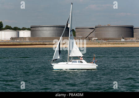 Ein Hunter Pilot 27 Yacht mit zwei Mannschaft vorbei an BP Hamble Oil Terminal in Hamble auf Southampton Wasser Südengland, Großbritannien. 2018. Stockfoto