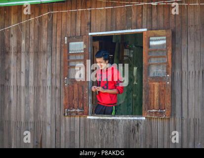 Inle See, Myanmar - Feb 7, 2018. Ein junger Mann stand in der Nähe der Fenster der Holz- Haus am Inle See, Myanmar. Stockfoto