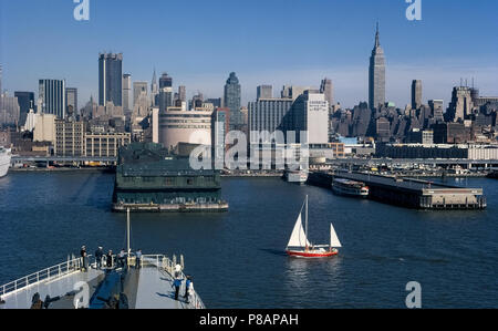 Die Skyline von New York City in New York, USA, als 1971 gesehen, von der Hudson River Vergangenheit Schiff Pfeiler und dem erhöhten West Side Highway (12. Avenue) Gebäude in Midtown Manhattan, einschließlich der hoch aufragenden Empire State Building auf der rechten Seite. Das Hafengebiet hat sich in Aussehen mit dem 21. Jahrhundert verändert - Gründung der Hudson River Park, Fußgänger- und Fahrradwege anschließen Freizeiteinrichtungen für viele Freizeit- und Sportmöglichkeiten. Historisches Foto. Von Michele & Tom Grimm urheberrechtlich geschützt. Stockfoto