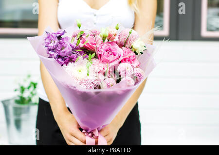 Junge Frau mit zarter Bouquet von Blumen auf der Straße in der Nähe von Flower Shop Stockfoto