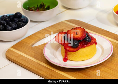 Vorbereitung shortcake Dessert mit frischen Erdbeeren, Blaubeeren, und Schlagsahne. Stockfoto