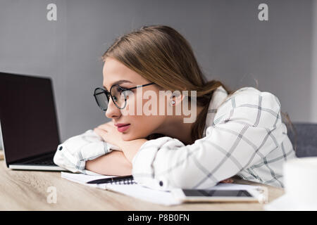 Gelangweilt junger Student Mädchen sitzen am Arbeitsplatz und Wegsehen Stockfoto