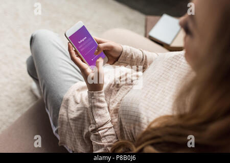 7/8 Schuß von Frau auf Sie ihr Smartphone mit Instagram App auf dem Bildschirm couch Stockfoto