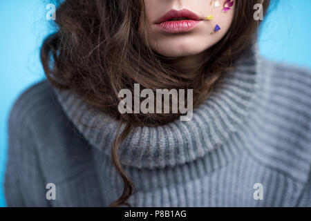 7/8 shot der jungen Frau in Rollkragen-pullover mit Blumen auf dem Gesicht Stockfoto