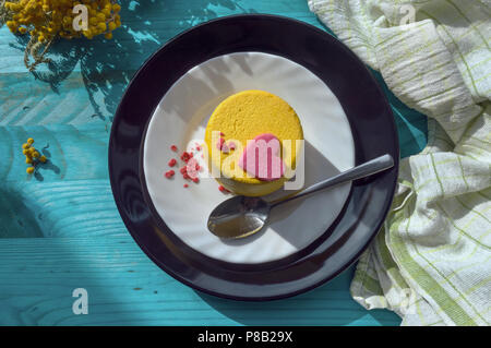 Blick von oben Der gelbe mini Kuchen mit rosa Herzen auf blauem Hintergrund Holz dekoriert Stockfoto