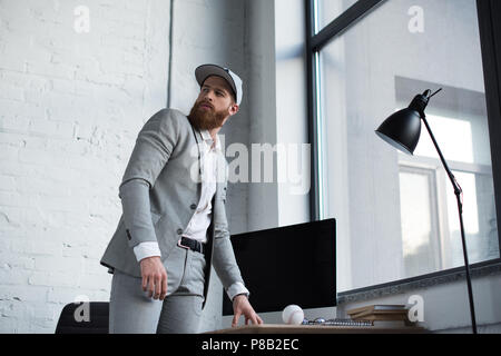 Unternehmer im Baseball Cap weg schauen im Büro Stockfoto