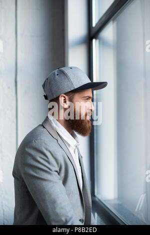 Seitenansicht der Geschäftsmann in Baseball Cap im Fenster suchen Stockfoto