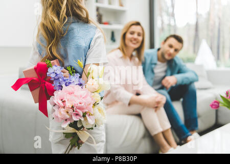 Selektiver Fokus der kleinen Tochter mit Geschenken für mathers Tag und Eltern auf dem Sofa zu Hause Stockfoto