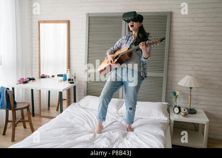 Asiatische Frau mit VR-Gerät headset Gitarre spielen video game mit Aufregung und Freude. Stockfoto