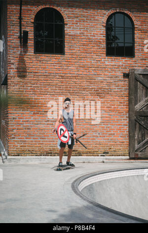 Stattliche skater Holding Straßenschild in der Nähe von Skatepark Stockfoto