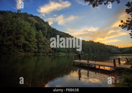 Ein Mann war entspannend auf hölzernen Brücke am Lakeside am Nachmittag. Stockfoto