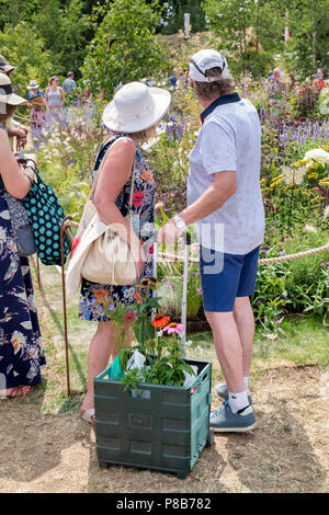 Menschen mit einem Wagen voller gekauft Pflanzen bei einer Show Garten an der RHS Hampton Court flower show suchen. London Stockfoto