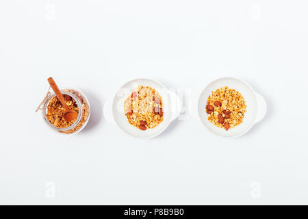 Zwei Schalen und Becher, mit Hafer Müsli auf weißem Tabelle ausgefüllt, Ansicht von oben. Flach minimale Zusammensetzung der hausgemachten Mutter Müsli Frühstück für Paare. Stockfoto