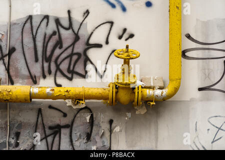 Gelbe Leitung mit einem Hahn Ventil auf der Straße Wand Stockfoto
