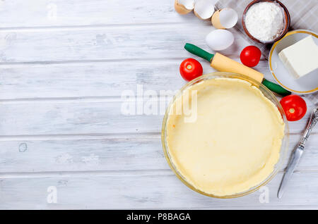 Raw Basis der Teig beim Backen in einer Auflaufform und Zutaten für die griechischen Pie mit Käse und Tomaten, Kopieren, Ansicht von oben Stockfoto