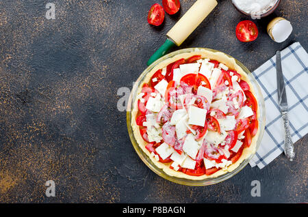 Raw Basis der Teig beim Backen in einer Auflaufform und Zutaten für die griechischen Pie mit Käse und Tomaten auf dunklem Hintergrund, Kopieren, Ansicht von oben Stockfoto